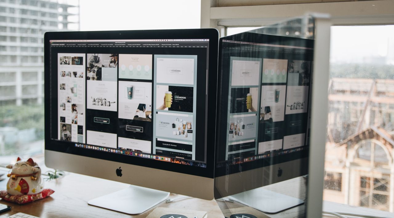about-us Dual monitors on a desk, showcasing web design in a modern office setting.